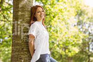 Portrait of a pretty redhead leaning against trunk