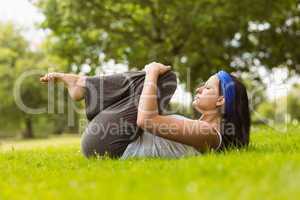 Content brunette doing yoga on grass