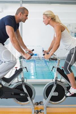 Side view of fit working on exercise bikes at gym