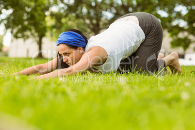 Calm brunette doing yoga on grass