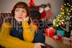 Pretty redhead thinking on the armchair at christmas