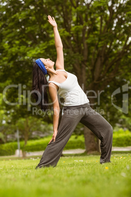 Cheerful brown hair doing yoga on grass