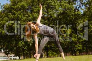 Pretty athletic redhead stretching in park