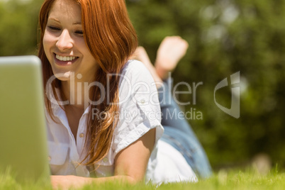 Pretty redhead happy and lying with her laptop