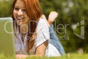 Pretty redhead happy and lying with her laptop
