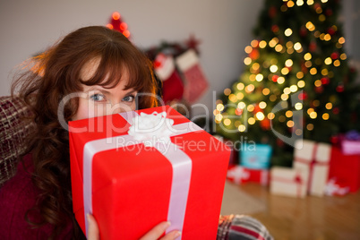 Redhead showing gift on the armchair at christmas