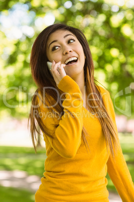 Cheerful woman using mobile phone in park