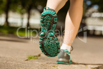 Woman in running shoes jogging on path