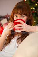 Pretty redhead sitting on couch drinking hot chocolate