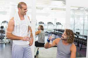 Smiling trainer talking to fit man at gym