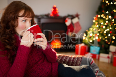 Pretty redhead drinking hot drink at christmas