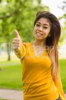 Beautiful woman gesturing thumbs up in park