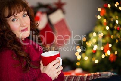 Pretty redhead holding mug of hot drink