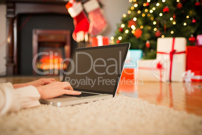 Redhead woman lying on floor using laptop at christmas