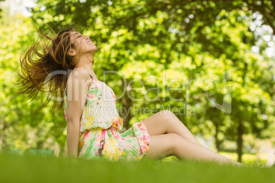 Relaxed young woman sitting on grass at park