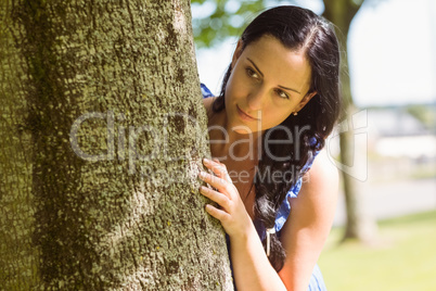 Pretty brunette leaning against a tree