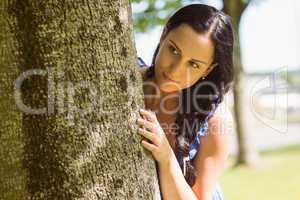Pretty brunette leaning against a tree