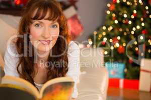 Pretty woman lying on a cosy couch reading book