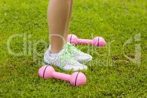 Woman with dumbbells on grass at park