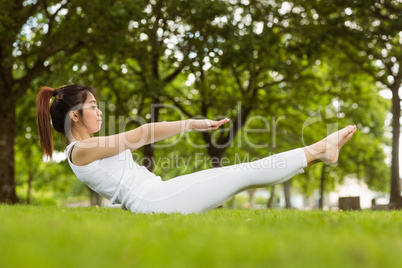 Side view of doing the boat pose in park