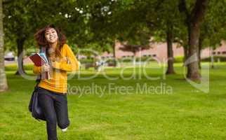 Female college student with books running in park