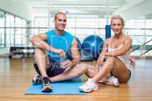 Fit couple sitting on floor at fitness club