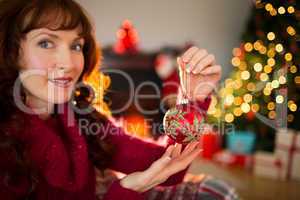 Smiling redhead holding red bauble at christmas