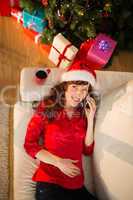 Redhead in santa hat lying on the sofa phoning