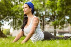 Smiling brunette doing yoga on grass