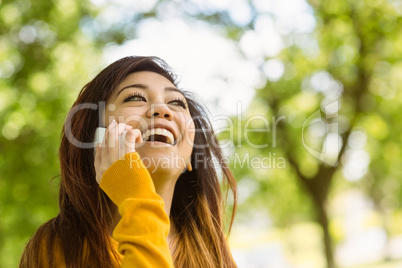 Cheerful woman using mobile phone in park