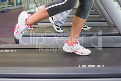 Low section of a couple running on treadmills at gym