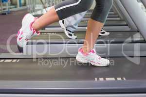 Low section of a couple running on treadmills at gym