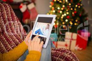 Redhead woman sitting on couch using tablet at christmas