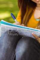 Mid section of student doing homework in park