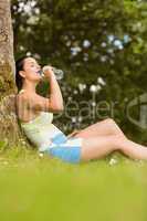 Fit brown hair sitting against tree drinking water