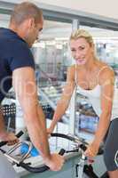 Smiling fit couple working on exercise bikes at gym