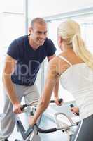 Smiling couple working on exercise bikes at gym