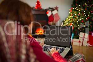 Redhead typing on laptop on the armchair at christmas