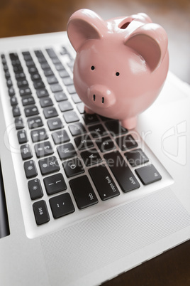 Piggy Bank Resting on Laptop Computer