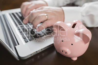 Piggy Bank Near Male Hands Typing on Laptop