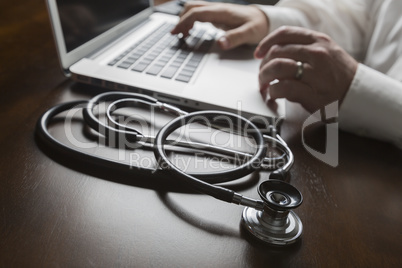 Stethoscope near Man Typing on Laptop Computer