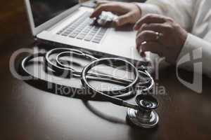 Stethoscope near Man Typing on Laptop Computer