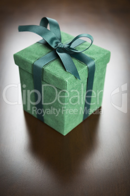 Green Gift Box with Ribbon and Bow Resting on Wood
