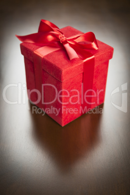 Red Gift Box with Ribbon and Bow Resting on Wood