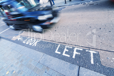 Lokk left sign on a London street with taxi cab fast approaching