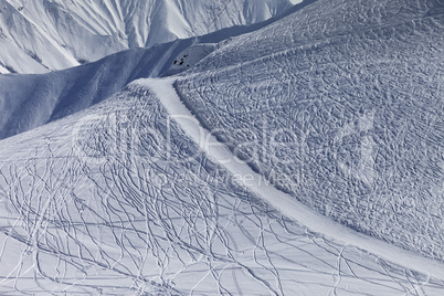Off-piste slope and road with trace from ski and snowboards
