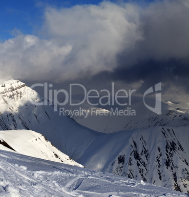 Off-piste slope and mountains with storm clouds