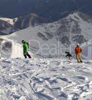 Snowboarders and skier on off-piste slope in sun evening