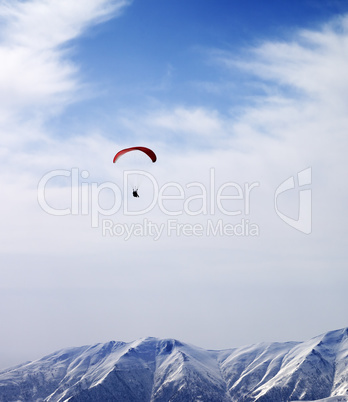 Paraglider silhouette of mountains in windy sky at sun day
