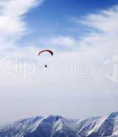 Paraglider silhouette of mountains in windy sky at sun day